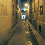 Ruelle étroite avec silhouette et trottinette électrique la nuit