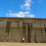 Personne regardant un grand mur en béton sous un ciel bleu