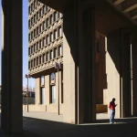 Homme sous les arches d’un immeuble moderne en plein jour