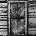 Fenêtre enveloppée d'un film plastique sur un mur en bois usé.
