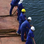 Ouvriers sur un quai regardant la mer