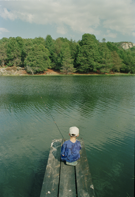 AKG924744.webp Enfant pêchant paisiblement sur un lac – Image 1