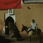 Deux personnes près d'un bâtiment avec drapeau marocain