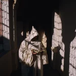 Moine en habit lisant un livre dans un couloir sombre