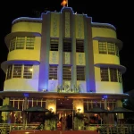 Édifice Art Déco Illuminé de Nuit avec Voiture Classique