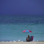 Personne Assise sous un Parasol sur une Plage de Sable