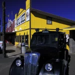 Taxi noir devant un restaurant jaune dans un décor de far-west